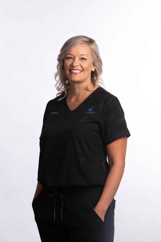 Britten, orthodontic assistant at Brodie Bowman Orthodontics, smiling in black scrubs