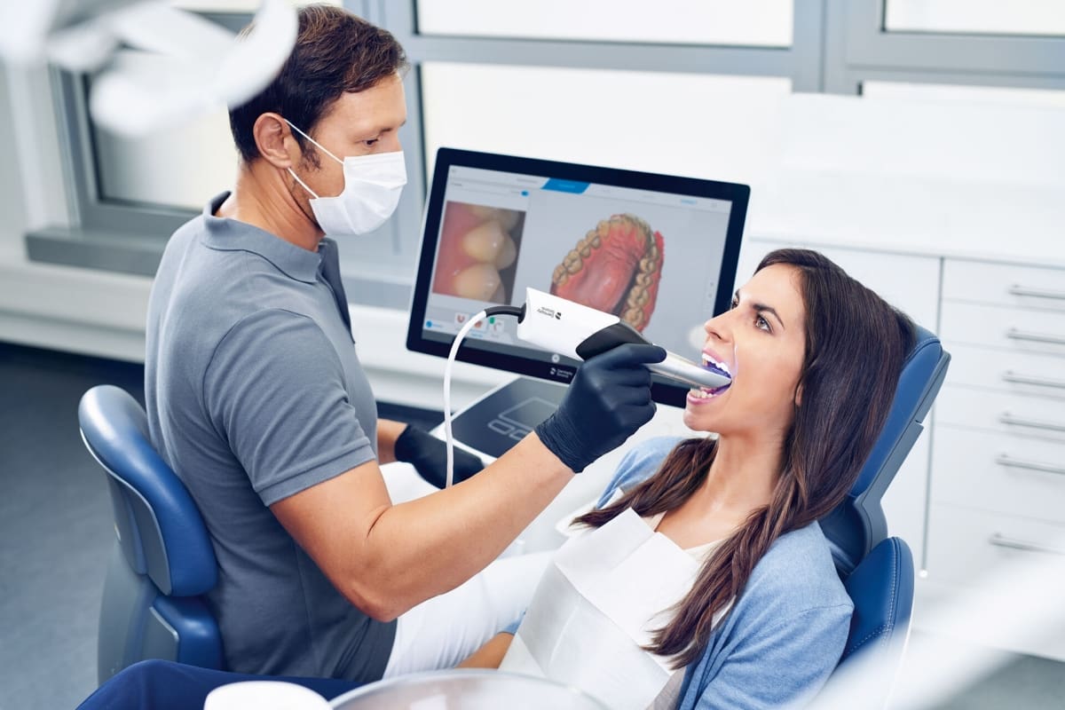 A patient having a digital scan taken, with her 3D tooth model on the chairside screen