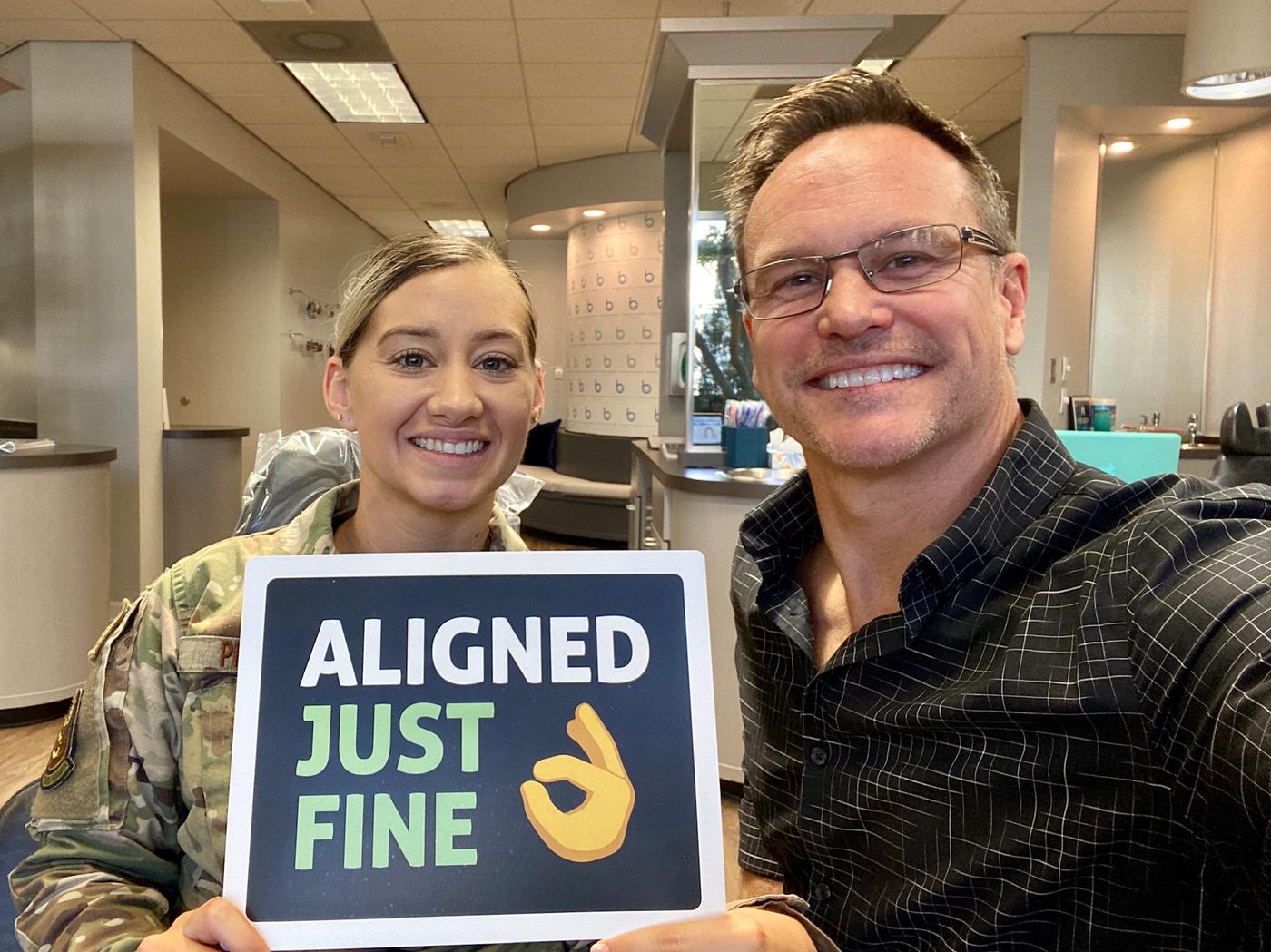 Dr. Bowman with an Air Force service member holding an Aligned Just Fine sign at Brodie Bowman Orthodontics